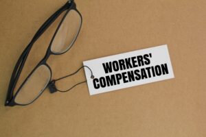 Glasses attached to a card that says “workers’ compensation.” State-by-state workers’ comp differences affect employees.